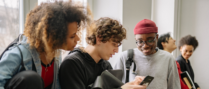 student looking at phone with other students