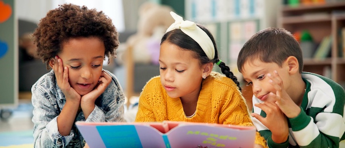 Three children reading book together