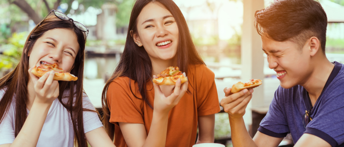 three people eating pizza together