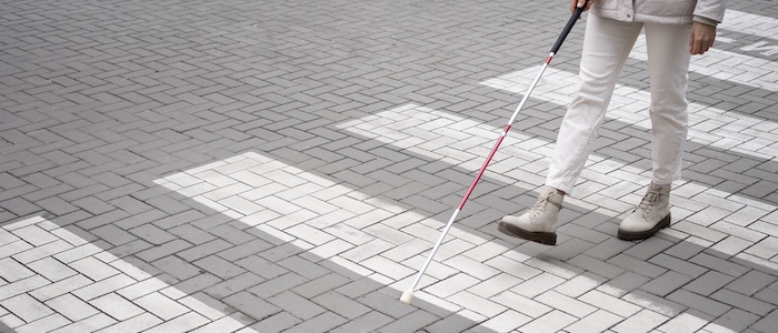 blind person using walking stick to cross the road