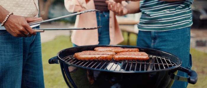 friends barbecuing sausages outside together