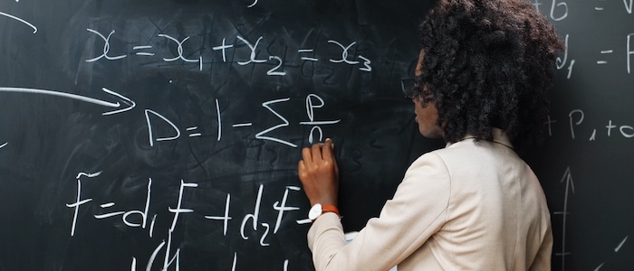 math student writing equation on chalkboard