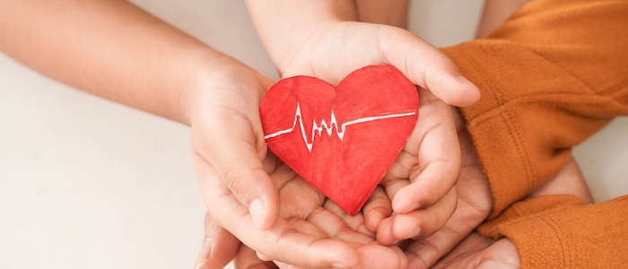 family holding heart together in overlapping hands