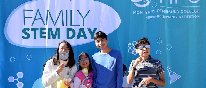 Children Posing Together in front of Family STEM Day Banner