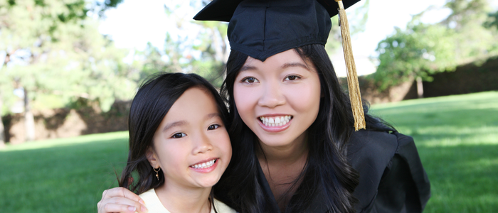 parenting college student posing in relgalia alongside child