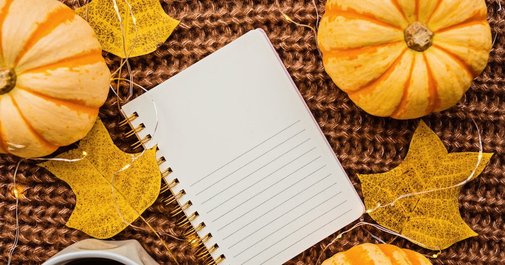 notebook next to pumpkins and leaves