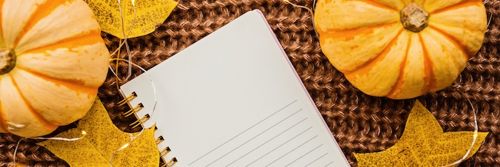 notebook next to pumpkins and leaves